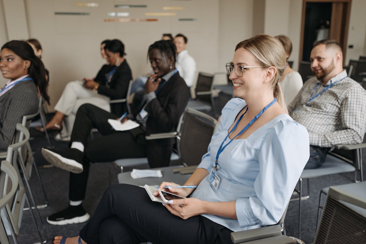 Woman in Blue Long Sleeve Shirt Sitting on Gray Chair Smiling